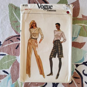 May include: A vintage Vogue Patterns sewing pattern envelope. The cover features illustrations of two women wearing different outfits. The envelope is off-white with the Vogue logo and pattern details. The size is 10.