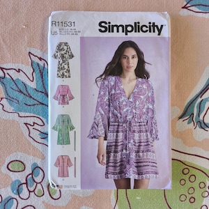 Peut inclure: Un patron de couture Simplicity, R11531, avec une femme portant une robe à imprimé cachemire. Le patron comprend des illustrations de différents styles de vêtements. Taille US 16-24, Euro 42-50, et taille Fil 44-52.