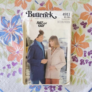 May include: Vintage Butterick sewing pattern 4911, featuring a man and woman modeling coats. The pattern cover has the text "FAST and EASY" and "Instant Fashion Patterns". The background is a floral fabric with orange, purple, and blue flowers.
