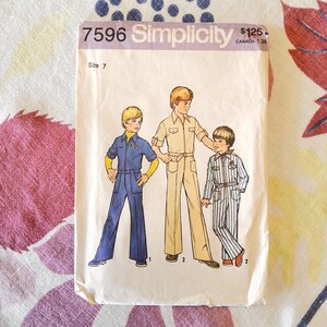 May include: Vintage Simplicity sewing pattern 7596 featuring illustrations of three children in jumpsuits. The pattern envelope is cream-colored with the text "7596 Simplicity" at the top. The size is 7.