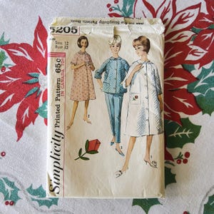 May include: Vintage Simplicity pattern envelope featuring illustrations of women's clothing designs. The envelope is cream-colored with the text "Simplicity Printed Pattern" and the price. The pattern is size 12, bust 32 inches. The background is a floral pattern.