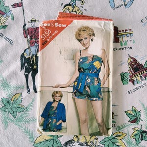 May include: A See & Sew 5156 sewing pattern envelope for size B (12-14-16) featuring a sleeveless romper with a blue waist tie and a matching jacket. The pattern cover displays a floral print garment in shades of teal, green, and yellow.