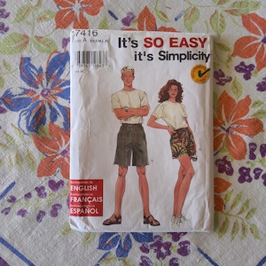 May include: A Simplicity sewing pattern packet with the text "It's SO EASY it's Simplicity". The packet features illustrations of a man and woman wearing shorts and t-shirts. The packet includes instructions in English, French, and Spanish.