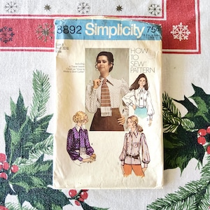 May include: Vintage Simplicity sewing pattern 8892 featuring illustrations of blouses. The pattern includes instructions for making a shirt collar. The package is cream-colored with blue and red text and images of the finished garments.