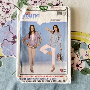 May include: A sewing pattern package featuring two women modeling tops and pants. The package has the text "Burda Young Fashion" and the number "7678". The text "All patterns with seam and hem allowances" is also visible.