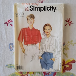 May include: Simplicity sewing pattern number 9839 for sizes 10-20. The pattern includes instructions for making two button-up shirts, one in red and one in white. The model wearing the red shirt is also wearing white trousers and a gold bracelet. The model wearing the white shirt is wearing blue jeans.