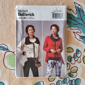 Puede incluir: Un patrón de costura "B6569 Butterick Katherine Tilton" con dos diseños de chaqueta. Una chaqueta es crema con cuello negro y estampado floral, la otra es roja con cuello azul marino. El tamaño del patrón es Xsm-Sml-Med.