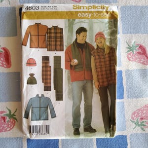 May include: Simplicity sewing pattern 4803 featuring a jacket, vest, hat, and scarf. The pattern includes images of the finished garments, with a man and woman modeling the clothing. The pattern is labeled "easy-to-sew".