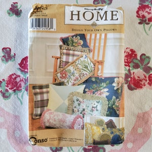 Könnte beinhalten: Ein Simplicity Home Nähmuster zum Entwerfen eigener Kissen. Das Muster zeigt eine Vielzahl von Kissen in verschiedenen Farben und Mustern, darunter florale, karierte und geometrische Designs. Das Muster enthält Anweisungen zum Nähen der Kissen und zur Auswahl der richtigen Stoffe und Verzierungen.