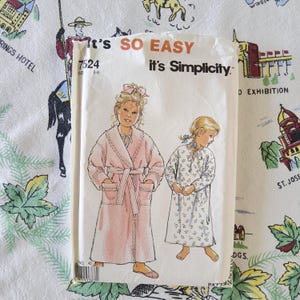 May include: A Simplicity sewing pattern envelope, number 7524, for sizes 3-8. The front features illustrations of a child wearing a pink robe with lace trim and a child wearing a long-sleeved white nightgown with a small blue floral print pattern.