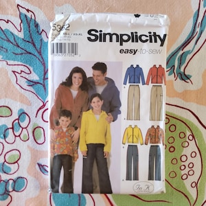 Puede incluir: Un paquete de patrones Simplicity easy-to-sew, talla XS-L/XS-XL. El paquete presenta a una familia con chaquetas y pantalones. El patrón incluye ilustraciones de chaquetas y pantalones en varios colores. El fondo es un estampado floral.