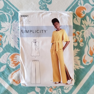 May include: A Simplicity sewing pattern packet, featuring a woman in a yellow outfit. The packet includes illustrations of a top and pants, with the text "EASY-TO-SEW" and size information.