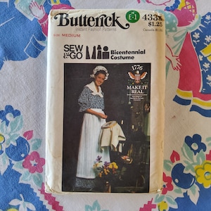 Puede incluir: Un patrón de costura vintage para un disfraz del Bicentenario. El patrón es de Butterick y es el número 4333. El patrón incluye instrucciones para hacer un vestido y un gorro. El patrón es para una talla mediana. El patrón es de la línea de patrones Sew & Go. El patrón incluye una imagen de una mujer usando el disfraz. El patrón es de 1976.
