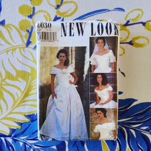 May include: A vintage New Look sewing pattern featuring a wedding dress design. The pattern cover displays a model in a white off-the-shoulder bridal gown. The size range is 8-18. The background is a floral pattern in yellow and blue.