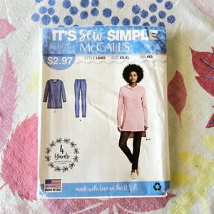 Puede incluir: Un paquete de patrones de costura McCall's con una mujer con una túnica rosa y leggings negros. El paquete incluye ilustraciones de una camiseta de manga larga y pantalones. El texto incluye "IT'S Sew SIMPLE", "MADE IN USA" y "made with love in the U.S.A."