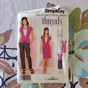 May include: Simplicity sewing pattern 1919 K5, featuring a pink suit with a ruffled jacket and skirt or pants. The pattern includes the text "Step by step to sewing success!" and "threads MAGAZINE COLLECTION".