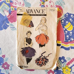 May include: Vintage Advance sewing pattern 7751 featuring illustrations of aprons. The pattern envelope is aged, with a yellowed price tag and the Advance logo. The illustrations show different apron styles, including a red and a purple apron.