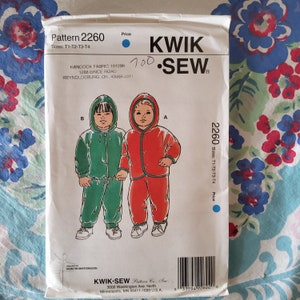 May include: A sewing pattern for a hooded jumpsuit for children. The pattern is for sizes T1-T2-T3-T4. The pattern is from Kwik-Sew Pattern Co., Inc. and is printed on white paper with blue and red illustrations.