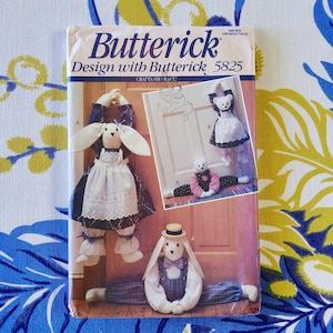 May include: A Butterick pattern for crafts, design 5825, with illustrations of handmade bunny and bear doorstops and decorative items. The cover has a blue and white floral background.