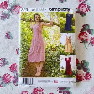 Puede incluir: Patrón de costura Simplicity 8231 con una mujer con un vestido floral rosa. El patrón incluye imágenes de vestidos en azul, beige y rojo. El patrón está diseñado e impreso en los EE. UU. Talla US 14-22.