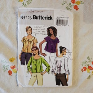 May include: A Butterick B5223 sewing pattern envelope featuring illustrations of four different blouse styles in yellow, purple, green, and white. The white paper envelope includes handwritten notes, a barcode, and size range F5 16-18-20-22-24.