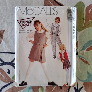 Peut inclure: Patron de couture McCall's pour vêtements French Toast. Le patron présente des illustrations d'enfants portant des tenues comprenant un gilet, une jupe et un pantalon. Le texte indique "You don't eat 'em. You wear 'em."