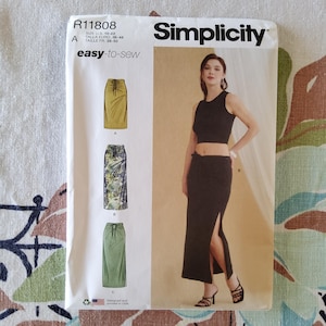 May include: Simplicity sewing pattern R11808. The pattern includes instructions for making a skirt. The pattern shows a woman wearing a black crop top and a black skirt with a side slit. The pattern is easy-to-sew and includes sizes 10-22.