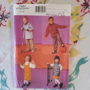 May include: A sewing pattern for children's clothing, featuring three different outfits. The pattern is for sizes 5-6-6X. The first outfit is a blue jacket with a white collar and a pair of beige pants. The second outfit is a red pullover sweater with a pair of beige pants. The third outfit is a yellow dress with a white bib and a pair of white tights.
