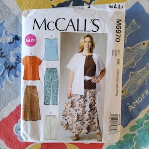 May include: A sewing pattern for a skirt, pants, and tops. The pattern is for sizes KK (26W-28W-30W-32W) and is labeled McCall's M6970. The pattern is labeled "Easy" and includes a white top with a brown undershirt, a pair of blue pants, a white skirt with a floral print, a brown skirt with a geometric print, and a light blue tank top.