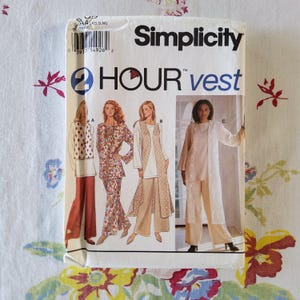 May include: A Simplicity 2 Hour vest sewing pattern envelope featuring illustrations of four different vest styles labeled A, B, and C. The white paper envelope displays the brand name, product title, and size range XS, S, M at the top.