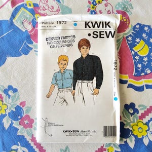 Puede incluir: Una taza de cerámica blanca con un asa negra y el texto "But First, Coffee" en negrita negra. La taza está sobre una superficie de madera. La taza mide 10 cm de alto.