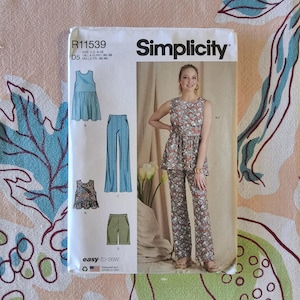 Puede incluir: Un patrón de costura Simplicity, R11539, con una mujer modelando un top y pantalones con estampado floral. El patrón incluye diseños para un top, pantalones y shorts. La talla es US 4-12. El texto "easy-to-sew" es visible.