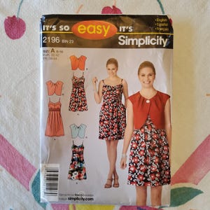 May include: Simplicity sewing pattern 2196, featuring a woman in a floral dress and bolero. The pattern includes various dress styles and bolero options. The package has the text "IT'S SO easy" and "Simplicity". Sizes A 6-16 are listed.
