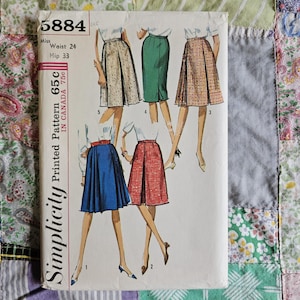 Puede incluir: Un sobre de patrón de costura Simplicity 5884 con ilustraciones de cinco variaciones de falda. El texto incluye Miss Waist 24, Hip 33 y 65c in Canada 75c. Las faldas se muestran en azul, rojo, verde, cuadros y patrones moteados.