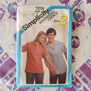 Op de afbeelding: Simplicity naaipatroon nummer 5226, Beginner's Choice niveau 2, maat 16 miss, voor een overhemd met kraag en korte mouwen. Het patroon toont twee modellen die het overhemd dragen, een in rood en een in blauw.