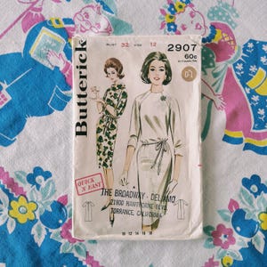 May include: A Butterick sewing pattern envelope 2907 featuring illustrations of two dresses with three-quarter sleeves and waist ties. The text includes 'Bust 32', 'Size 12', '60c', 'Quick N Easy', and 'The Broadway - Del Amo, 21800 Hawthorne Blvd, Torrance, California'.