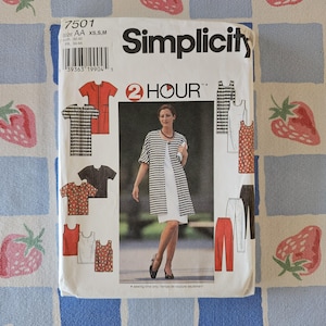 Può includere: Una busta per cartamodello Simplicity 7501 per taglie XS, S, M. Il fronte presenta una fotografia di una persona che indossa una giacca aperta a motivi bianchi e neri sopra un abito bianco, con illustrazioni di vari top, pantaloni e vestiti.