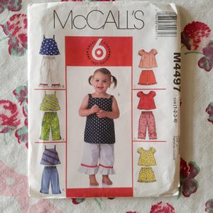 Peut inclure: Patron de couture McCall's M4497 pour les tailles 1-2-3-4. Le patron comprend six looks différents pour une tenue de bébé fille. Les tenues comprennent un haut sans manches avec un bas à volants, un haut à manches courtes avec un bas à volants et un pantalon avec une bordure à volants.