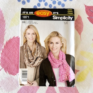 May include: Simplicity sewing pattern 1871. The pattern features a woman wearing a scarf. The pattern's cover has the text "It's So Easy" and "Simplicity". The pattern is one size and includes English, Spanish, and French instructions.