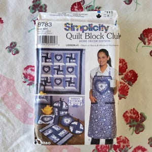 Puede incluir: Un patrón de Simplicity Quilt Block Club para un proyecto de decoración del hogar. El patrón es para la lección n.º 1, Corazón de corazones y patchwork de molino de viento. El patrón incluye instrucciones para hacer un bloque de colcha, un delantal y agarraderas para ollas. El patrón es azul y blanco con un diseño de corazón.