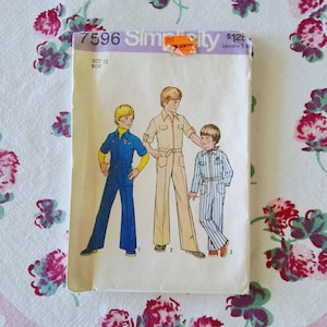 May include: Vintage Simplicity sewing pattern 7596 for boys' jumpsuits. The pattern envelope features illustrations of three boys in different jumpsuit styles. The envelope is cream-colored with text and a price tag.