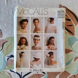 May include: A McCall's sewing pattern envelope featuring images of brides wearing various wedding veils and headpieces. The pattern number is 2057. The envelope has the text "McCall's" at the top and "Alicyn" at the bottom.