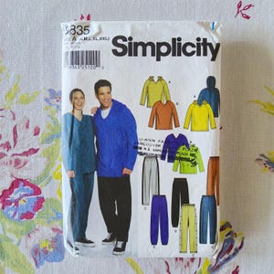 May include: A Simplicity sewing pattern envelope 9835 for size A, including S, M, L, XL, and XXL. The front shows illustrations of hooded and V-neck tops and pants in various colors, along with a photograph of two people wearing the finished garments.