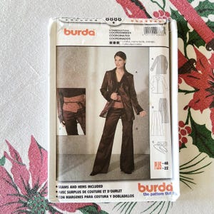 May include: A Burda sewing pattern package showing a woman in a brown suit. The package includes illustrations of a jacket, top, and trousers. The text on the package includes "SEAMS AND HEMS INCLUDED" and "the pattern that fits".