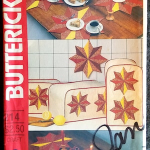 Könnte beinhalten: Ein Vintage-Bastelmuster zum Nähen von sternförmigen Tischläufern, Platzsets und Brotauflagen. Das Muster zeigt ein rotes und gelbes Sternendesign mit goldener Einfassung. Das Muster stammt von Butterick und trägt die Nummer 214. Der Preis beträgt 2,50 €.