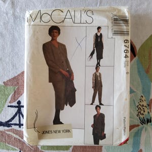 May include: Vintage McCall's sewing pattern featuring a woman in a brown suit. The pattern includes multiple views of the suit, with the text "McCall's" at the top and "JONES NEW YORK" at the bottom. Size 6.