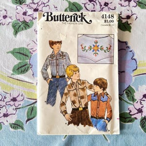 May include: Vintage Butterick sewing pattern 4148 featuring illustrations of boys' shirts with floral embroidery and plaid details. The pattern includes a close-up of the embroidered design. The text "Butterick THE FASHION ONE" is at the top.