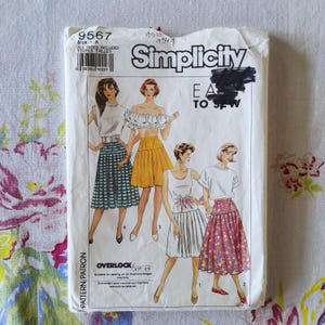 May include: A white Simplicity sewing pattern envelope 9567 featuring illustrations of four different outfits including skirts and tops. The text includes Simplicity, Easy to Sew, and Overlock/Serger. The envelope shows a barcode and size A.