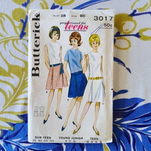 Può includere: Modello di cucito Butterick vintage per adolescenti, con illustrazioni di tre diversi modelli di abiti. La busta del modello è bianca con testo nero, tra cui il marchio, la taglia e il prezzo. Le illustrazioni raffigurano abiti con gonne e top in vari colori.