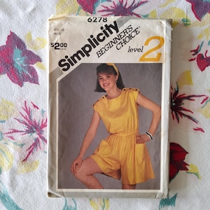 May include: Vintage Simplicity Beginner's Choice sewing pattern, level 2, size 16. The pattern features a yellow romper with a matching belt and pockets. The image on the pattern shows a woman wearing the romper. The pattern is from the USA.